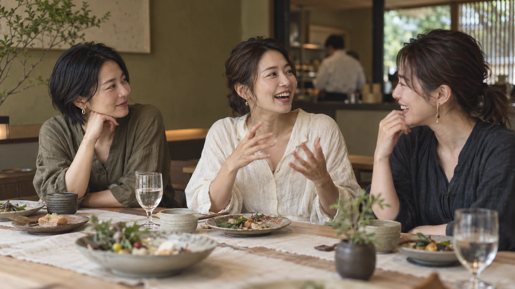 食卓を囲み、友人の近況に耳を傾ける三人