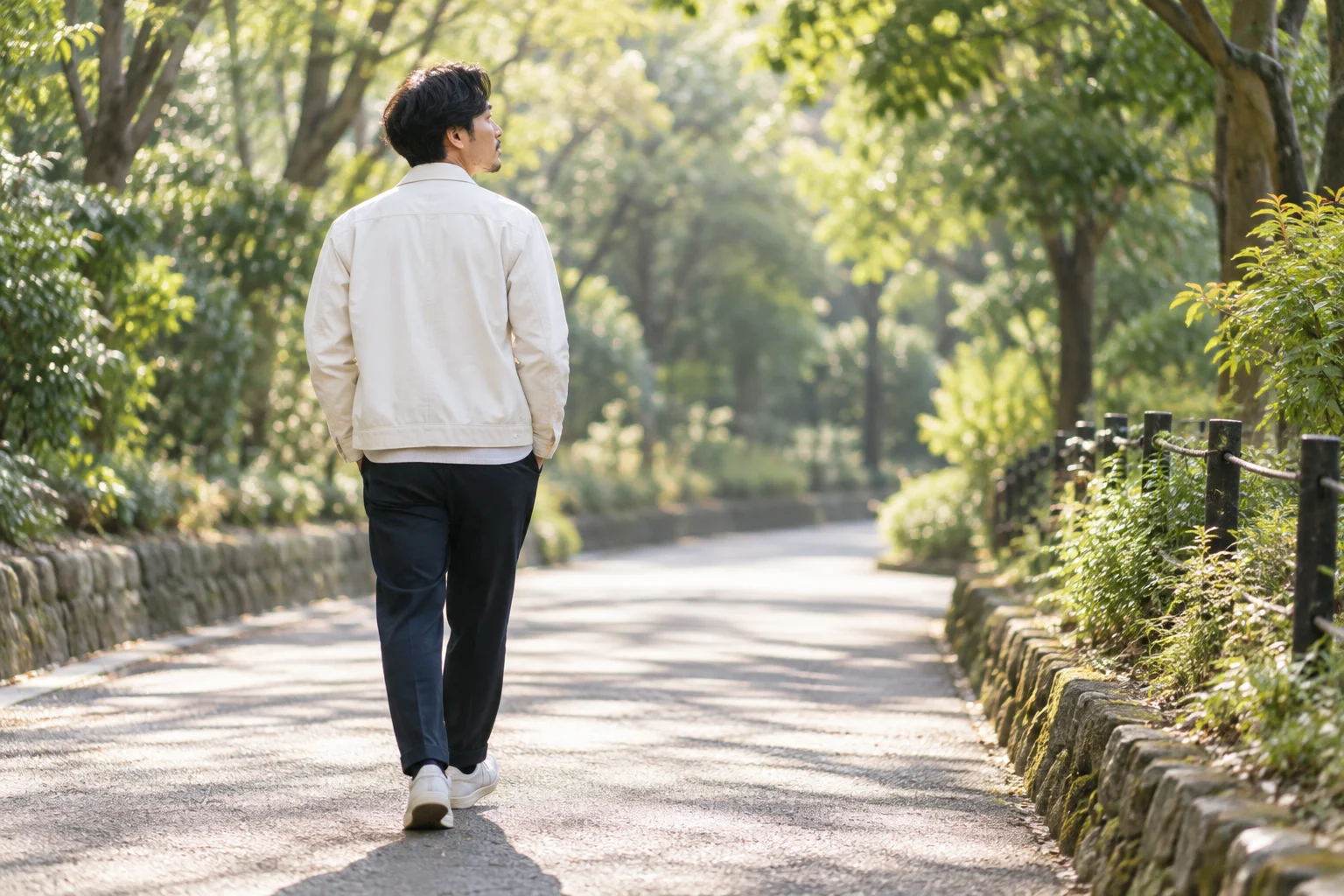 緑のある公園で歩きながらひと息つく男性