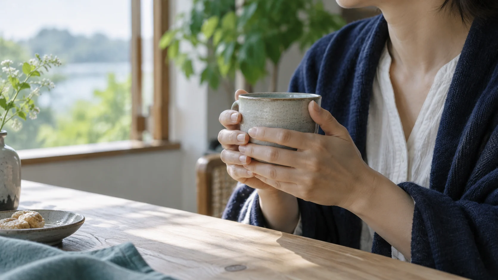 温かいカップに手を添え、窓辺で休む様子